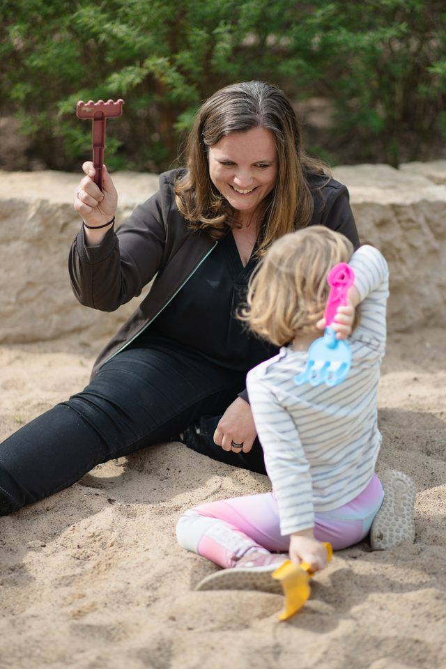 Marie Scharfenberg spielt mit einem Kind im Sandkasten